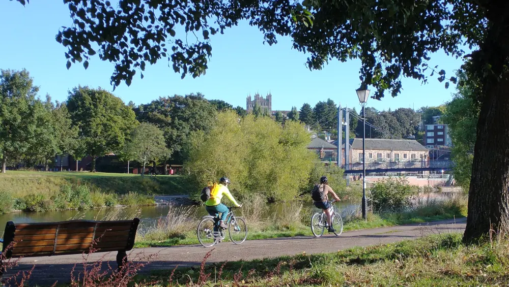Cyclists riding towards Exeter Quayside with Exeter Cathedral visible in the distance