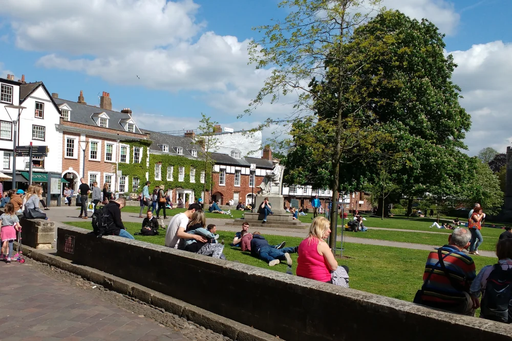 People relaxing on Cathedral Green in Exeter during sunny weather