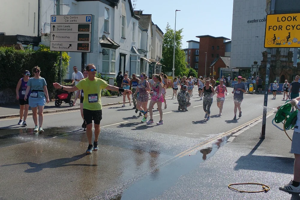 Runners being sprayed with water from hosepipe during Exeter Great West Run