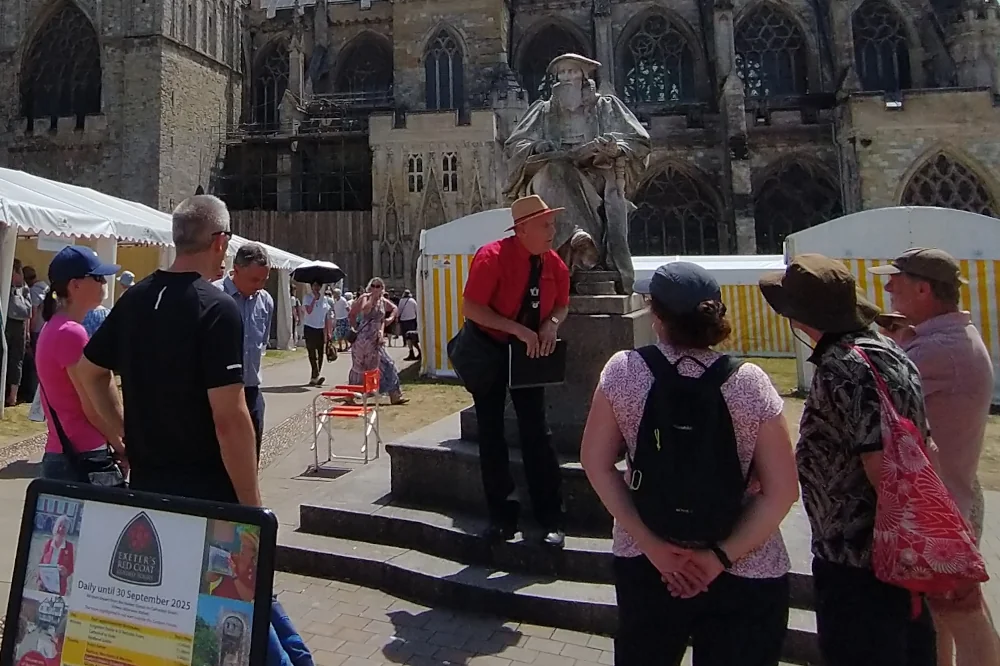 Exeter Red Coat Guide with a walking tour gathered at the Hooker Statue on Cathedral Green